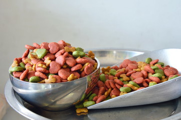 pet food in stainless bowl and iron scoop on weighing scale