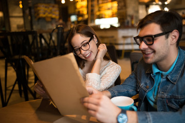 Young couple looking to the menu and choose a dish in cafe