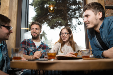 Group of friends sitting at table in cafe having fun