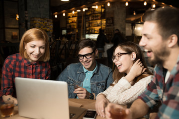 Friends in cafe watching notebook and having fun