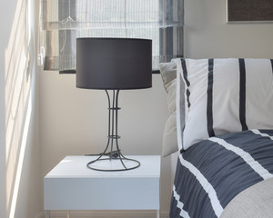 Ready lamp with black shade lamp on bedside table with striped p