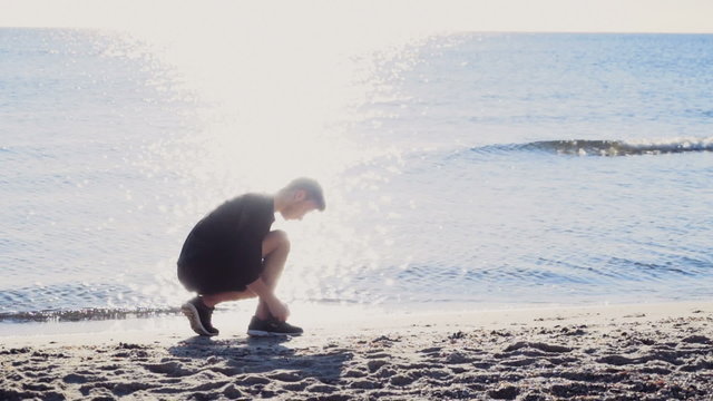male runner tying  his shoelaces in the sun light on the beach slow motion