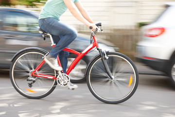 Fototapeta na wymiar Cyclist At Speed Along Urban Street
