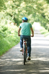 Rear View Of Young Man Enjoying Cycle Ride In Countryside