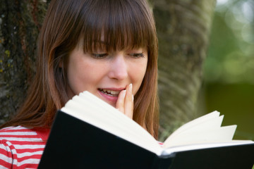 Young Woman Shocked By Reading Novel Outdoors
