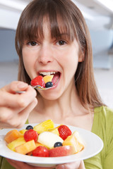 Young Woman Eating Bowl Of Fresh Fruit Salad