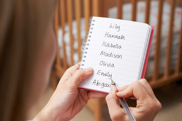 Woman Writing Possible Names For Baby Girl In Nursery