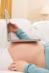 Obraz na płótnie Canvas Pregnant Woman With Laptop Computer Resting On Belly