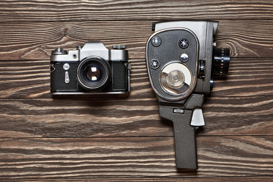 Retro SLR camera and mechanical movie camera on wooden backgroun