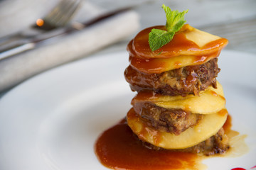 Calf's liver with apples Laid layers with sauce on a white plate