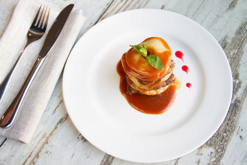 Calf's liver with apples Laid layers with sauce on a white plate