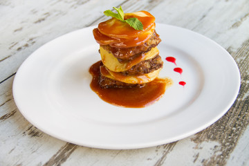Calf's liver with apples Laid layers with sauce on a white plate