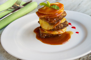 Calf's liver with apples Laid layers with sauce on a white plate