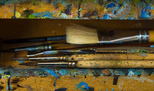 Artist paintbrushes closeup on old wooden easel