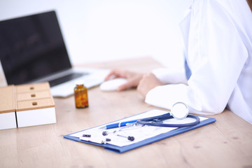 Female doctor sitting on the desk and working a laptop in hospi
