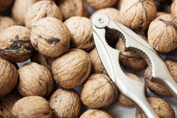 Walnuts in a bowl with tongs for cracking nuts, top view