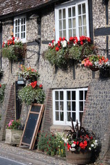 Fototapeta na wymiar Quaint Old British Pub Decorated with Window Boxes and Hanging Baskets of Flowers in Summer.