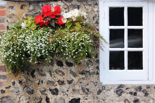 Quaint Old British Pub Decorated With Window Boxes And Hanging Baskets Of Flowers In Summer.