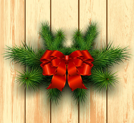 Christmas wooden background with fir branches and red bow with ribbon.
