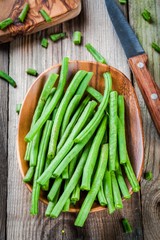 pods of fresh organic green beans in a wooden bowl