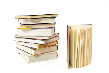 Pile of books and one open book on white background