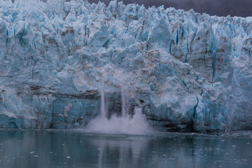 A mass of ice calves from the glacier in Glacier Bay National Park, Alaska