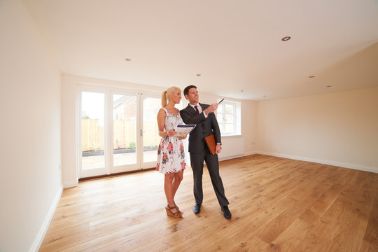 Estate Agent Showing Young Woman Around New Empty Property