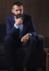 Businessman sitting the sofa in office lobby, isolated on dark 