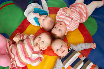 Fototapeta na wymiar Overhead View Of Babies Lying On Mat At Playgroup