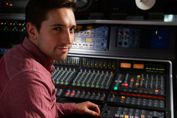 Obraz na płótnie Canvas Engineer Sitting At Mixing Desk In Recording Studio