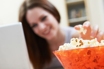Woman Eating Popcorn Whilst Watching Movie On Laptop