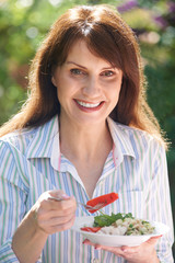 Attractive Middle Aged Woman Eating Healthy Salad In Garden