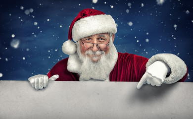 Santa Claus pointing in white blank sign with smile