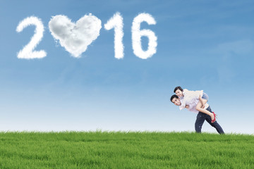 Couple having fun at field with numbers 2016