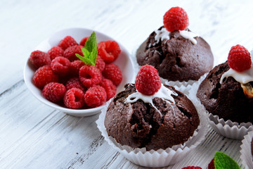 Delicious chocolate cupcakes with berries and fresh mint on wooden table close up