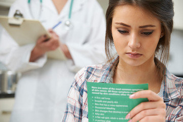 Teenage Girl Reading Leaflet In Doctor's Surgery