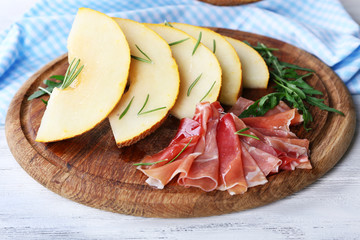 Melon with prosciutto of Parma ham on wooden table, closeup