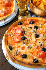 Pizza served with beer on wooden table