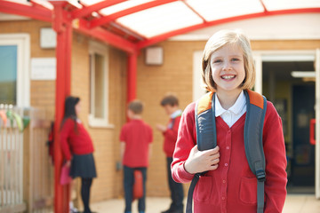 Girl Wearing Uniform Standing In School Playground