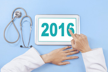 Doctor hand touching number 2016 on the tablet