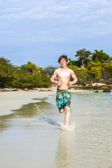 young boy with red hair jogging along the tropical beach