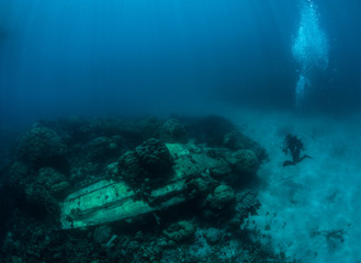 Scuba diver exploring crushed in WWII Japanese airplane Zero. Micronesia
