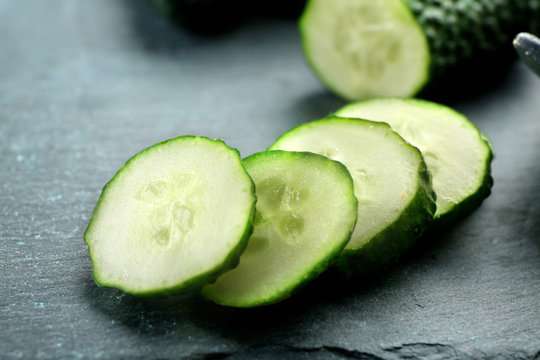 Sliced cucumbers on black background, close up