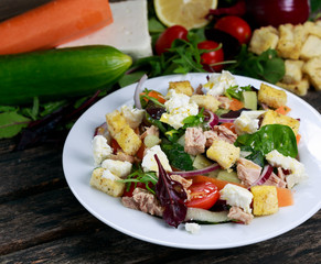 Tuna salad with Spinach, rocket, red ruby chard, tomatoes, cucumbers, carrot, red onion, white chesse, croutons. on old wooden table