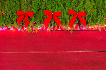 Blank red wood sign with holiday lights and green garland border with velvet bows