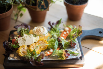 Baked vegetables: corn, carrots, greens and cheese with cream cheese on a plate

