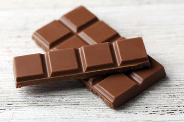 Black chocolate pieces on color wooden background