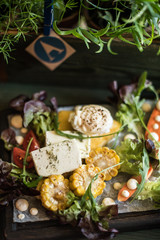 Baked vegetables: corn, carrots, greens and cheese with cream cheese on a plate
