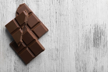Black chocolate pieces on color wooden background