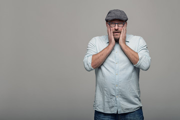 Nachdenklicher Mann fasst sich im Gesicht an